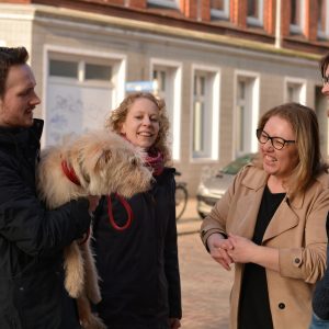 Özlem Ünsal im Gespräch mit drei Personen, von denen eine einen Hund auf dem Arm hat,. Alle sind fröhlich.